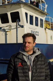 Captain Jake Anderson stands in front of his boat, the Saga, at dock.