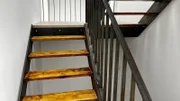 Die Stahltreppe mit Stufen aus alten Gerüstbohlen führt von Erdgeschoss über das Obergeschoss bis ins Dachgeschoss.