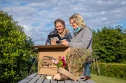 Veronika Kram (li.) und Ina Fischer schauen sich hier an der "Überraschungskiste" das Vorstellungsvideo von Stephanie Fröhlich an.