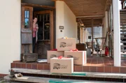 Hannah stellt die gepackten Überraschungskisten zur Abholung vor der Tür ab.