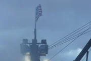 In hazy weather, the American Flag waves proudly above the mast of the Time Bandit.