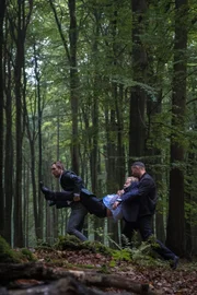 Mühsam schleppen Angelo (Frederick Lau l.) und Claude (Murathan Muslu l.) den tot geglaubten De Groot (Roland Koch M.) in den Wald.