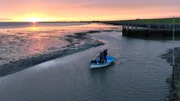 Früh morgens bei Niedrigwasser gelangen die Gebrüder Hellmann nur mit dem kleinen Beiboot zu ihrem Passagierschiff, mit dem sie Exkursionen ins Watt unternehmen.