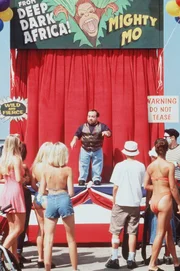Der Schausteller Herbert Crane (Danny Woodburn) macht Geschäfte mit einem zahmen Affen.