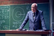 Der strenge Physiklehrer Herr Findeis (Jochen Kolenda) blickt von oben herab auf Julian und Ernst. Kann Julian seinen eigenen ehemaligen Lehrer davon überzeugen, Ernsts kritischen Notenstand zu verbessern?
