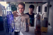 Julian (Ben Münchow, l.) hat eine Mission: Er will Ernst (Diyar Ilhan, r.) dabei helfen, seinen Schwarm mit einer fetten Hausparty zu beeindrucken. Dazu muss erst einmal der Getränkestand gecheckt werden.