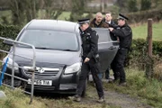 Stephen Mason (Michael Wildman, 2.v.l.), Stiefvater der verschwundenen Maggie, wird von der lokalen Polizei, darunter DCI James Belmont (Chris Reilly, 2.v.r.) verhaftet. (Komparsen im Bild.)