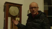 Wissenschaftmoderator Karsten Schwanke mit einer Pendeluhr, die einst die Sternzeit maß.