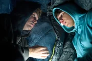 Provisorisch in Schlafsäcke gewickelt liegen Julian (Ben Münchow, l.) und Ernst (Diyar Ilhan, r.) vor der Notaufnahme, wo Ernsts gebrochene Nase behandelt werden soll. Die hat er einem versehentlichen Fausthieb des Schuldirektors Stöfgen zu verdanken.