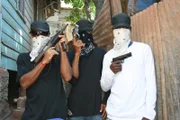 Location: Kingston, Jamaica: Mid shoot of three dealers in bandanas with firearms. A gang from Kingston who protect the community from rival gangs and also drug bases. They also rob and sell weed to buy guns and ammo.