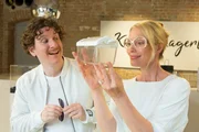 Assistent Thorben (Dominik Weber) überreicht seiner Chefin Karla Lagerloef (Katja Weitzenboeck) ein kostbares Geschenk.