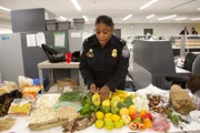 Officer Arrisia Sima lays out seized food that is prohibited from entering the country.