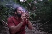Surama, Guyana - Hazen carefully uses his breath to ignite the embers to make fire.