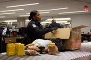 Officer Arrisia Sima inspects a passenger's package filled with food products.