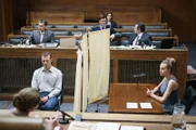 Chloe (Nadia Parkes, r.) sitzt bei der Vorverhandlung hinter einem Sichtschutz, um nicht direkt mit MD(Julian ?wie?ewski, 2.v.r.) konfrontiert zu werden. Anwesend sind auch dessen Verteidiger Cosmo De Rose (Fabrizio Matteini, l.) sowie Francesco (Lorenzo Richelmy, 3.v.l.), Nicoletta (Elenora Romandini, 3.v.l.) und Staatsanwalt Storari (Sergio Romano, 2.v.l.).