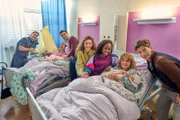Raúl (Nico Stank, l.), Juli (Johanna Wieking, 2.v.l.), Flo (Anton Weil, 3.v.l.), Amelie (Eva Luca Klemmt, M.), Nikita (Karmela Shako, 3.v.r.), Lena (Anna Schimrigk, 2.v.r.) und Milan (Slavko Popadic, r.) sind alle froh, dass die Babys endlich auf der Welt sind.