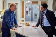 Phil (Adrian Edmondson, l.) spricht mit einem Sonderermittler der Polizei (Narinder Samra, r.) über den Auftrag in Mailand, den er Chloe vermittelt hatte.