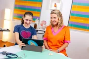 Doc Christine (r.) erklärt Flora (l.), warum wir überhaupt krank werden.