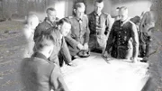 Hitler und Generäle stehen über einem Kartentisch.