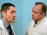 Prof. Simoni (Dieter Bellmann, rechts) weist Dr. Kaminski (Udo Schenk) darauf hin, dass er soeben eine direkte Anweisung des Professors in den Wind geschlagen hat. In seiner zynischen Art weist Kaminski Simoni darauf hin, dass die beiden Glück hatten, dass Hans-Peter Brenner nicht Zeuge dieses Grenzübertrittes geworden ist.