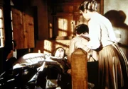 Laura Ingalls-Wilder (Melissa Gilbert, l.) ist während eines Tornados von einem Balken getroffen worden. Ihre Eltern Caroline (Karen Grassle, r.) und Charles (Michael Landon, M.) trösten die Verletzte.