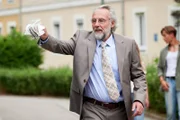 Herr Schneider (Daniel Friedrich) traut seinen Augen nicht: Ist das sein Enkelsohn, der sich da vorne auf die Straße geklebt hat?
