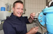 Alexander Herrmann zapft an der Quelle ein Glas Wasser bei der Siegsdorfer Petrusquelle (Lkr. Traunstein, Oberbayern).