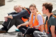 Finn (Adrian Grünewald, r.) ist heute zum ersten Mal bei einer Protestaktion dabei, aber will sich seine Aufregung auf keinen Fall anmerken lassen. Schon gar nicht vor Lena (Valerie Stoll, M.). Die fragt sich jedoch, warum Finn so angespannt schaut.
