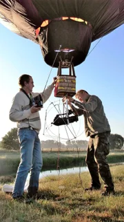 Kameramann Ralph Schieke (r.) und Ballonpilot Jürgen Meier bereiten den Modell-Heißluftballon für Flugaufnahmen im Artland vor.
