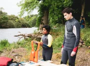 Glen (Krish Misra l.) und Louis (Oliver Cunliffe) sollen zusammen auf einem Floss in See stechen. Glen findet es gar nicht lustig, dass für ihn nur noch eine kleine Schwimmweste verziert mit Kinderbildern übrig ist.