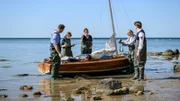 Peter Braun (Thomas Welsand, M.) liegt neben Champagner-Flaschen und Kaviar tot in seinem Segelboot. Dr. Helene Sturbeck (Katharina Blaschke, 2.v.l.) und Roswitha Prinzler (Silke Matthias, 2.v.r.) können eine Wunde am Kopf feststellen. Hat jemand den Toten, mit dem der Kommissar Lars Pöhlmann (Dominic Boeer, l.) früher selbst segelte, erschlagen und am Strand zurückgelassen?