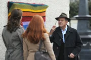 Bürgermeister Schattenhofer (Werner Rom) wundert sich, wer den Schaukasten mit einer Strickdecke verhängt hat.