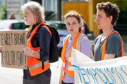 Die Aufregung steigt! Alle bereit? Lena (Valerie Stoll, M.) gibt das Kommando, woraufhin sich Henning (Joachim Seemann, l.) und Finn (Adrian Grünewald, r.) auf die Straße setzen sollen und ihre Hände auf den Asphalt kleben.