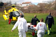Die Heli-Crew trägt Julian zum Hubschrauber.