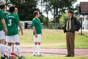 Hubert und Staller (Helmfried von Lüttichau, r.) kommen zum Training, um der Mannschaft vom Tod ihres Mitglieds zu berichten. Die Spieler sind entsetzt.