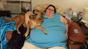 Jeanne is lying in a chair with a dog.