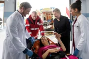 Nancy Lenz (Elisabeth Baulitz, M.) und ihr Mann Kai (Jörg Witte, 2.v.r.) sind unter Alkoholeinfluss zusammen eine Treppe hinuntergestürzt. Dr. Marc Lindner (Christian Beermann, l. mit Komparse, 2.v.l.) und Vivienne Kling (Jane Chirwa, r.) kümmern sich um die erheblich verletzte, aber gut gelaunte Nancy.