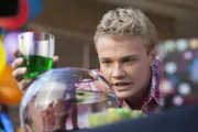 Cam (Dominic Deutscher) schaut ungläubig in das Goldfischglas. Wie kann es sein, dass Evie dort als Mini-Meerjungfrau herumschwimmt?