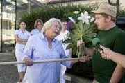 Die tatkräftige Vroni (Christiane Blumhoff) hält die Journalisten von der Klinik fern, lässt aber den Blumenboten (Roland Schreglmann) durch.