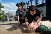 Da Tarik (Serhat Cokgezen, M.) und Claudia (Janette Rauch, l.) vor dem Notarztwagen am Einsatzort sind, muss Tarik bei dem Verletzten (Max Kidd, r.) eine Mund-zu-Mund-Beatmung durchführen.
