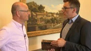 Karsten Schwanke (links) im Gespräch mit dem Generalsekretär des Deutschen Archäologischen Instituts (DAI), Philipp von Rummel, in Berlin. Rummel hält die Erstausgabe der archäologischen Nachrichten aus dem Gründungsjahr des Instituts 1829 in Händen.