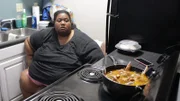 Kelly sitting in front of a stove cooking.
