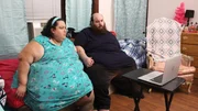 Vianey and Allen are looking at a laptop, holding hands.