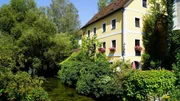 Haus am Wehrgrabenkanal mit Blumen und Bäumen