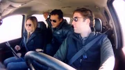 Erin Ryder, James Fox und Ben McGee sehen sich im Auto Filmmaterial auf einem iPad an.