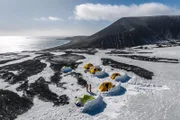 Mitglieder des Expeditionsteams stehen im Basislager auf Saunders Island, Südliche Sandwichinseln. Jedes Zelt hat eine Wand aus Schnee und Eis zum Schutz vor den Elementen.