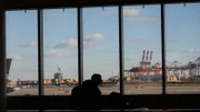 Ein Passagier geht an einer Fensterwand vorbei, die das Rollfeld des Newark Liberty International Airport zeigt. (National Geographic)