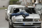 Schneider hat seinen Entführer Brandt (Robert Gallinowski) mit einem plötzlichen Bremsmanöver auf die Motorhaube befördert, um ihn loszuwerden.