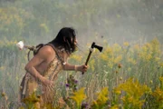 Ein indianischer Mann hält eine Axt in der Hand.