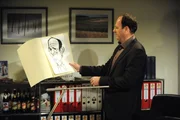 Hubert (Bernhard Ulrich) hofft, dass die Karikatur in seinem Büro vor Martin sicher ist.
